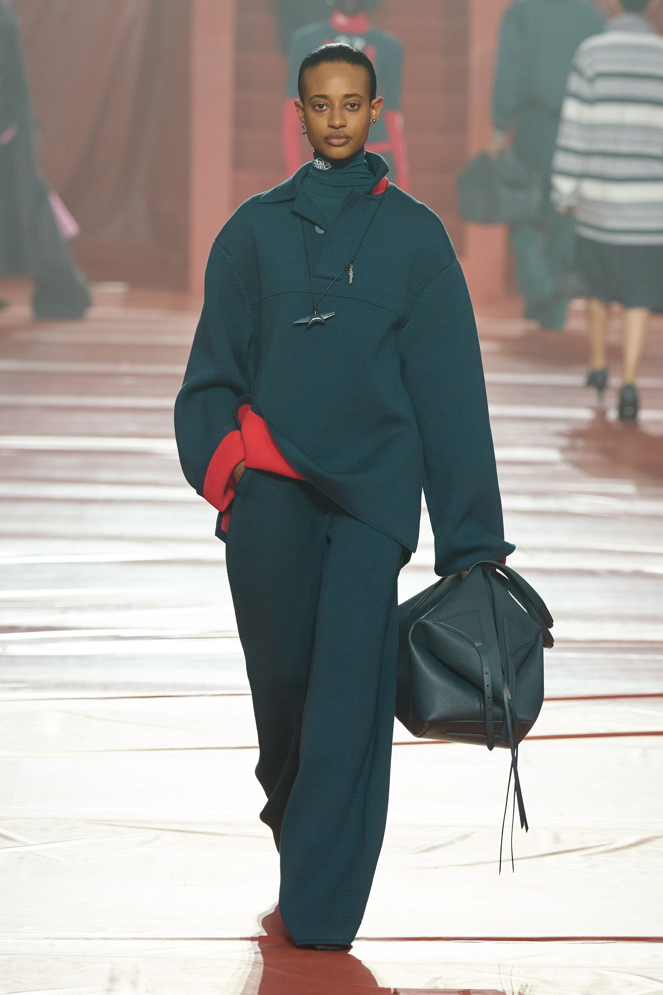 这一季 Lacoste 将品牌最核心的运动基因彻底升级为都市机能时装：酒红色尼龙运动外套、宽体运动裙、拉链高领和oversize运动风衣贯穿整场，经典网球白与深绿被重新调和成更成熟的学院运动色谱。轮廓保持宽松与机能感，但通过女性化中长裙、修身针织和高跟鞋完成优雅转换，使运动不再只是休闲，而是城市女性的日常盔甲-顽石频道趋势研究
